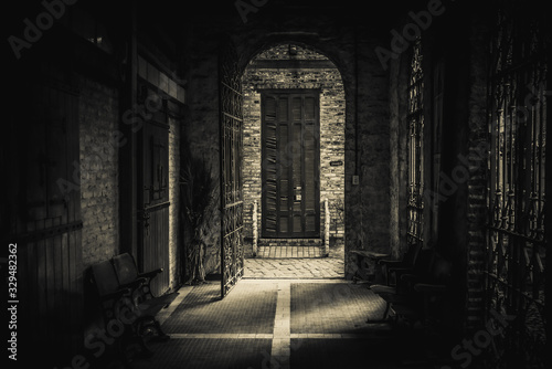 Cuadros en Lienzo Drawing-like view of scary passage leading to an old brick arch with a rusty open iron gate, heading to a broken blind