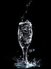 Wall Mural - Water with splashes in a glass on a black background