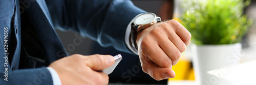 Fotomural Man in suit and tie check out time at silver wristwatch closeup