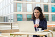 © Mangostar - Focused businesswoman using laptop in outdoor cafe. Serious middle aged businesswoman working with laptop computer while sitting at table with coffee outdoors. Technology concept