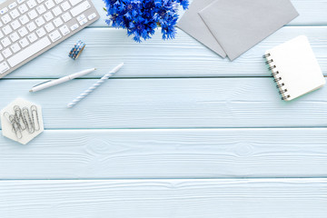 Wall Mural - Summer vibes at work. Office desk with cornflowers bouquet on blue wooden background top-down frame copy space