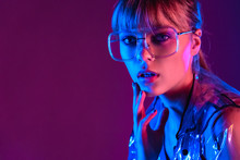 Chic Attractive Fashion Sexy Young Woman Girl Beauty Face Wear Stylish Trendy Transparent Raincoat Eyewear Glasses Look At Camera In Neon Light Purple Blue Studio Background, Portrait, Copy Space.