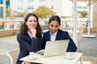 © Mangostar - Happy businesswomen with laptop in outdoor cafe. Cheerful female colleagues sitting at table, drinking coffee and using laptop computer in outdoor cafe. Wireless technology concept