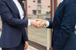 © Mangostar - Cropped shot of businesswomen shaking hands. Close-up partial view of female colleagues in formal wear shaking hands and greeting each other on street. Business handshake concept