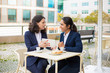 © Mangostar - Businesswomen drinking coffee and using tablet pc. Professional female coworkers in formal wear sitting at table and drinking coffee together in outdoor cafe. Coffee time concept