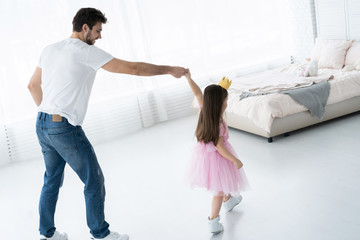 Wall Mural - I love you, dad! Handsome young man is dancing at home with his little girl. Happy Father's Day!