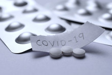 White Pill Tablet With Paper Text COVID-19. Corona Virus Flu Dose Of Medicine Or Treatment Drug Concept