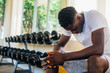 © twinsterphoto - Desperate African American male athlete sitting on bench during break in fitness training in modern gym