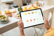 © rh2010 - Woman shopping food online using a digital tablet at the kitchen, close-up view on a tablet screen. Concept of buying online using mobile devices