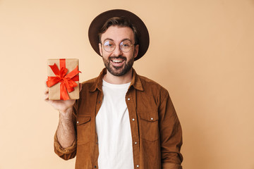 Wall Mural - Optimistic young unshaved man holding present box.