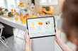 © rh2010 - Woman shopping food online using a digital tablet at the kitchen, close-up view on a tablet screen. Concept of buying online using mobile devices