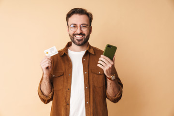 Poster - Positive man holding credit card using mobile phone.