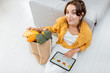 © rh2010 - Young woman shopping online using a digital tablet, sitting with bag full of products at home. Concept of buying online using mobile devices