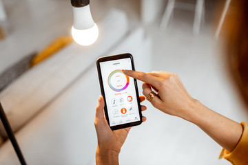 Controlling light bulb temperature and intensity with a smartphone application. Concept of a smart home and managing light with mobile devices