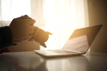 man holding dslr camera near laptop work place