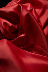 Poster - close up view of red soft and crumpled silk textured cloth isolated on black