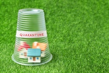 Coronavirus Quarantine Concept. Small House Covered With Transparent Plastic Cup And Inscription Quarantine