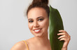 © Pixel-Shot - Beautiful African-American woman with tropical leaf on light background