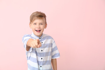 Wall Mural - Happy little boy pointing at viewer on color background