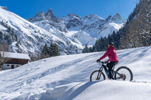 Nice Senior Woman Riding Her Electric Mountainbike On A Sunny Winter Day In The Allgau Alps Near Oberstdorf, Bavaria, Germany