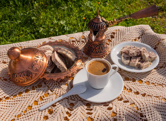 Wall Mural - Greek (Turkish) brewed coffee and marble halva on a table with a handmade tablecloth and a copper coffee maker and candy maker on a Sunny day