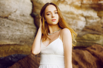 Wall Mural - Gorgeous girl in a long white dress on the ocean at the beach. The model is inherited by nature. Girl on vacation, light dress, summer, fashion. Gorgeous long hair develops in the wind. Tenerife