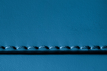 Texture of blue genuine leather sewn with stitch. For fashionable modern background, copy space