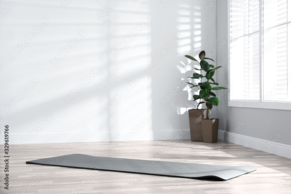 Unrolled grey yoga mat on floor in room - obrazy, fototapety, plakaty 