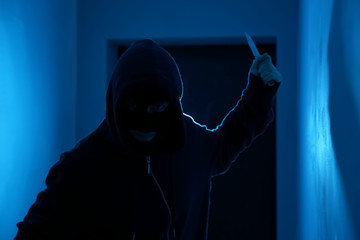 Wall Mural - Man with knife in dark room. Dangerous criminal