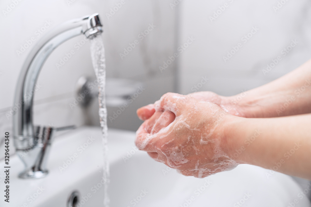 woman cleaning her hands with soap on faucet to protect from virus. - obrazy, fototapety, plakaty 
