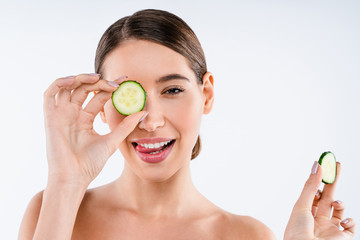 Sticker - Young woman holding slices of cucumber over isolated white background