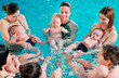 canvas print picture - A group of mothers with their young children in a children's swimming class with a coach.