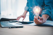 Businessman Hand Holding Lightbulb With Office Tools  On Desk. Idea, Innovation Inspiration Concept.