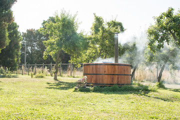 Wooden bathtub in the garden of my house with a fireplace to burn wood and heat water, that's why the smoke comes out