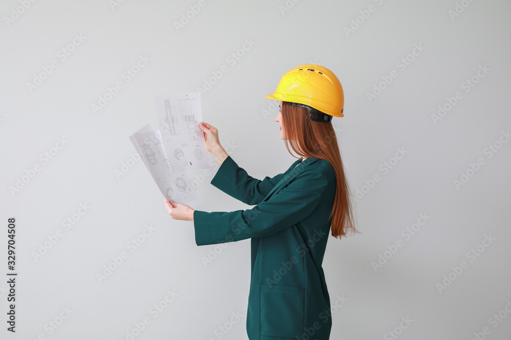 Female engineer with drawings on light background