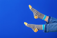 Legs Of Young Woman In Striped Socks On Color Background