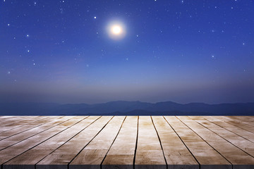 Wall Mural - wooden table desk with starry night sky and moon against mountains view in the dark night