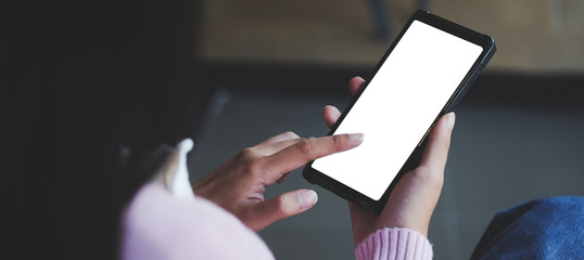 Cropped shot view of man hands holding smart phone with blank copy space screen for your text message or information content, female reading text message on cell telephone during in urban setting. 