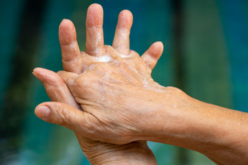 Senior woman's hands washing her hands using soap foam in step 2 on bokeh blue swimming pool Close up shot, Select focus, Prevention from covid19, Coronavirus, Bacteria, Healthcare, 7 step wash hand