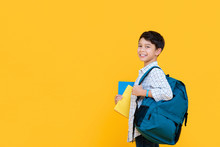 Happy Smiling 10 Year-old Mixed Race Boy With Backpack And Books Ready To Go To School Isolated On Yellow Background With Copy Spcae