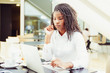 © Mangostar - Focused female office worker using computer in coffee shop. African American business woman working on laptop in cafe and looking away. Internet technology concept