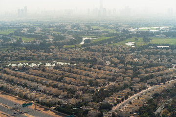 Wall Mural - Aerial view of Dubai with villas and houses of local residents on foreground and high-rise skyscrapers buildings in morning dusk on background, United Arab Emirates.