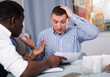 © JackF - Upset man with friend looking worriedly at papers at home