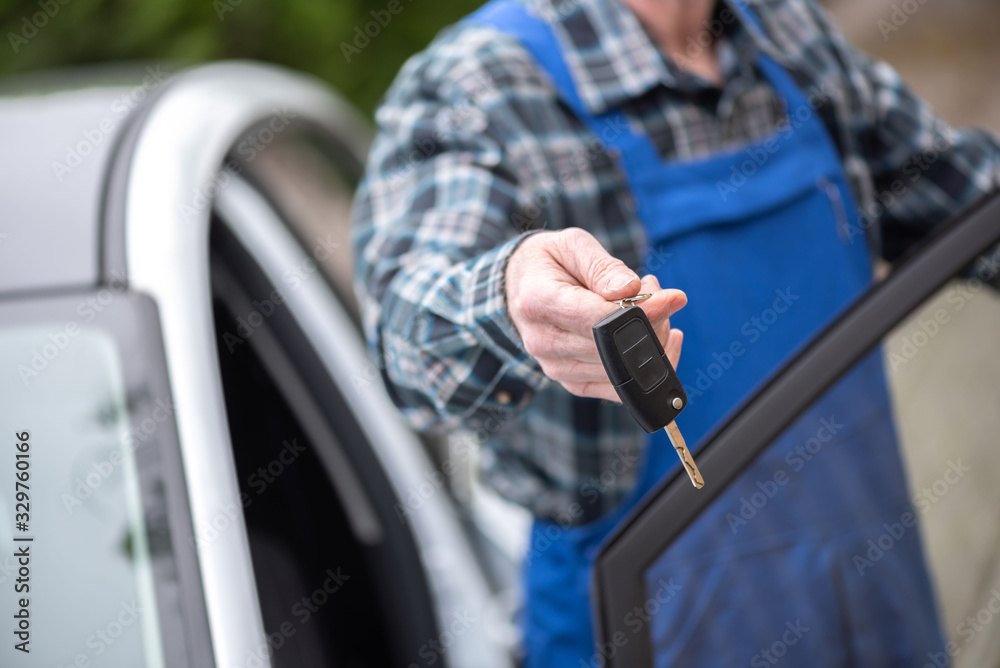 Mechanic delivering car keys after car engine checking - obrazy, fototapety, plakaty 