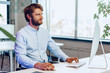 © fotofabrika - Young bearded businessman using his computer in a modern office place. Business concept