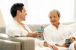 © karelnoppe - Middle aged couple sitting on couch in bathrobes.