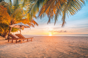beautiful tropical sunset scenery, two sun beds, loungers, umbrella under palm tree. white sand, sea