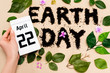 Cropped view of woman holding calendar with 22 april inscription near earth day lettering on beige