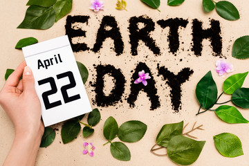 Wall Mural - Cropped view of woman holding calendar with 22 april inscription near earth day lettering on beige