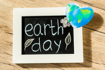Wall Mural - Top view of board with earth day lettering and globe on wooden background